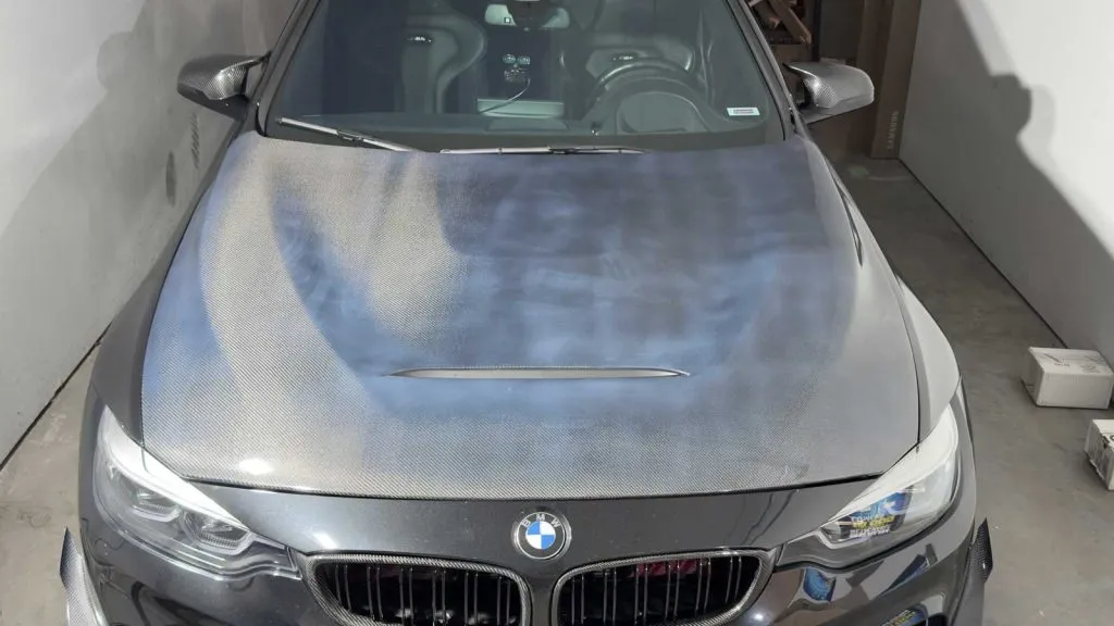 poor quality carbon fiber hood shown on a black bmw m4