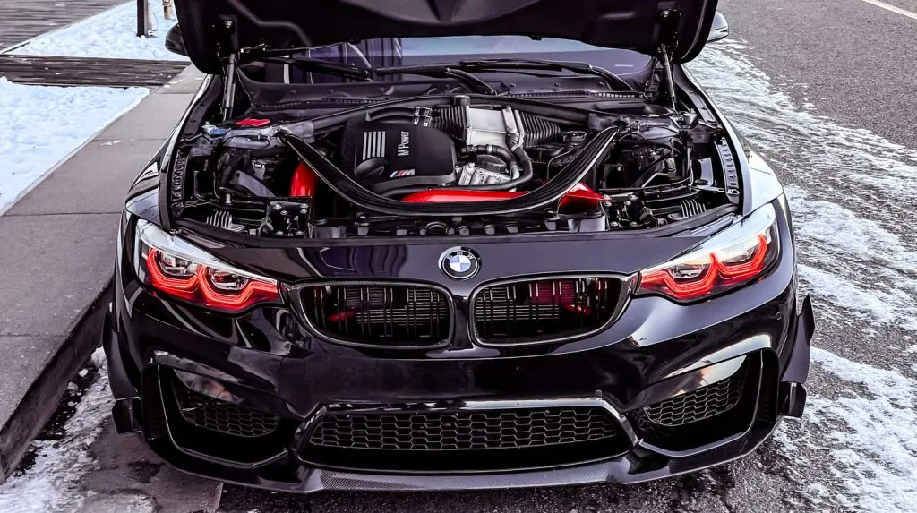 black bmw m4 that's modded with red VRSF front mount intakes