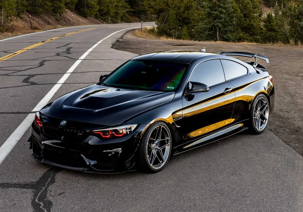 modded black f82 bmw m4 parked on a side of a mountain road